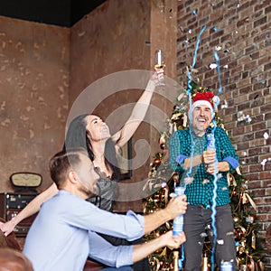 Group of happy three friends having fun with confetti and champagne at New Year`s party