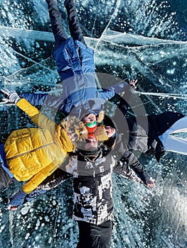 Group of happy tourist friends on background of ice winter lake Baikal