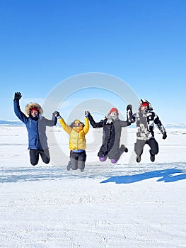Group of happy tourist friends jumping on background of ice