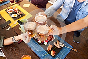 Group of happy unrecognizable friends drinking and toasting beer at brewery bar restaurant. Friendship concept