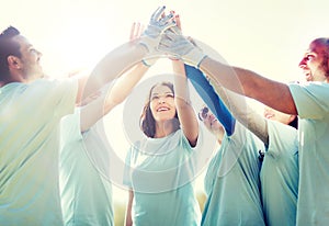 Group of happy volunteers making high five in park