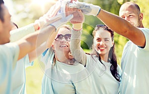 Group of happy volunteers making high five in park