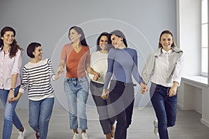 Group of happy women walking hand in hand, showing mutual support and solidarity