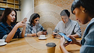 Group of happy young Asia friends having fun a great time and using smartphone together while sitting together at cafe restaurant