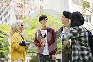 A group of happy young Asian-diverse college students are enjoying talking in the campus park