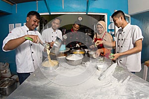 Group of happy young asian pastry chef preparing dough with flour, profesional chef working at kitchen photo