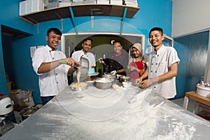 Group of happy young asian pastry chef preparing dough with flour, profesional chef working at kitchen photo