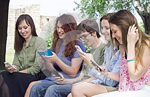 Group of happy young college students looking at mobile phones i