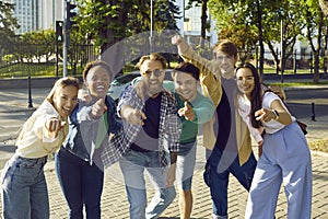 Group of happy young diverse people on city street smiling and pointing fingers at you