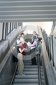 Group of happy young female students going up the escalator