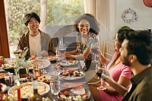 Group of happy young friends is drinking wine while having holiday dinner home party together