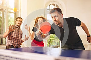 Group of happy young friends playing ping pong table tennis photo