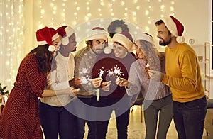 Group of happy young friends with sparklers having fun at a Christmas party at home