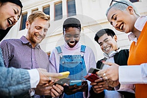 Group of happy young friends using mobile phone outdoors