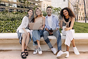 Group of happy young interracial people looking at camera spending time studying for exams.