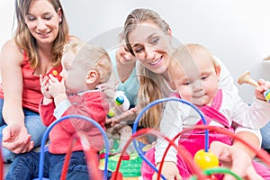 Group of happy young mothers watching their cute and healthy babies play