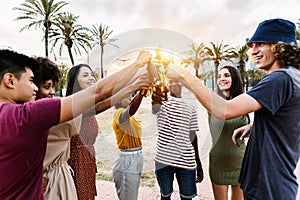 Group of happy young multiracial friends with drinks celebrating in summer party