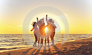 Group of happy young people dancing at the beach on beautiful summer sunset