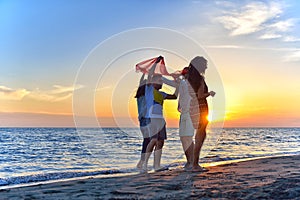 Group of happy young people dancing at the beach on beautiful summer sunset