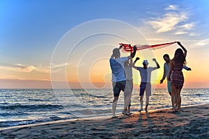 Group of happy young people dancing at the beach on beautiful summer sunset