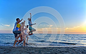 Group of happy young people dancing at the beach on beautiful summer sunset