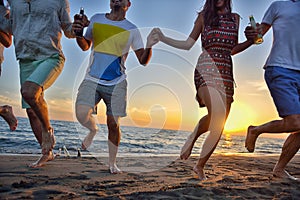 Group of happy young people dancing at the beach on beautiful summer sunset