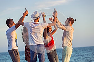 Group of happy young people dancing at the beach on beautiful summer sunset