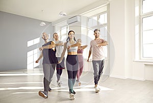 Group of happy young people doing sports exercises together while training in fitness studio.