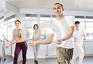 Group of happy young people enjoying a contemporary dancing class. Team of smiling dancers in casual wear practising new