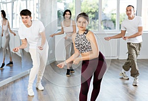 Group of happy young people enjoying a contemporary dancing class. Team of smiling dancers in casual wear practising new