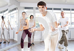 Group of happy young people enjoying a contemporary dancing class. Team of smiling dancers in casual wear practising new