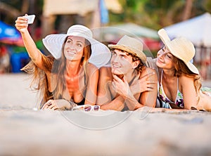 Group of happy young people lying on wite beach