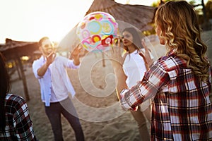 Group of happy young people playing with ball on beach