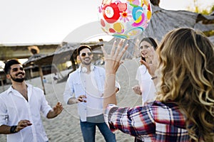 Group of happy young people playing with ball on beach