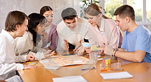 Group of happy young people playing board game