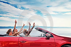 Group of happy people in red convertible car