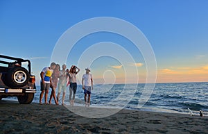 Group of happy young people is running on background of sunset beach and sea