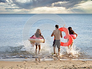 Group of happy young people running at the beach on beautiful summer sunset, friendship freedom vacation and travel holiday