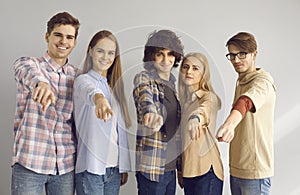 Group of happy young people standing together and pointing at camera choosing you