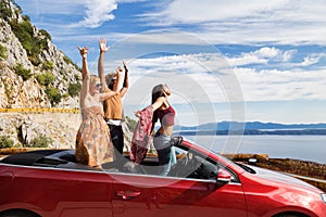 Group of happy people in red convertible car.