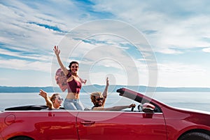 Group of happy people in red convertible car