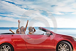 Group of happy people in red convertible car.