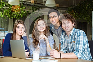 Group of happy young students sitting at the table