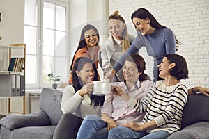 Group of happy young women drinking coffee, laughing and enjoying fun time together