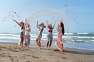 group of happy young women throwing up petals