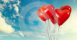 Group of heart shaped red air baloon on blue sky with clouds. Valentines day and romance concept.