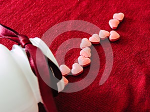 Group of hearts tablets with a white bottle on a red cloth background. Valentines day photo