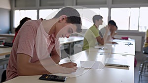 Group of high school students doing an exam at classroom.