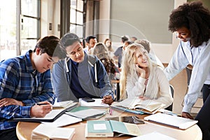 Group Of High School Students With Female Teacher Working At Desk