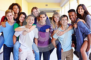 Group Of High School Students Giving Piggybacks In Corridor